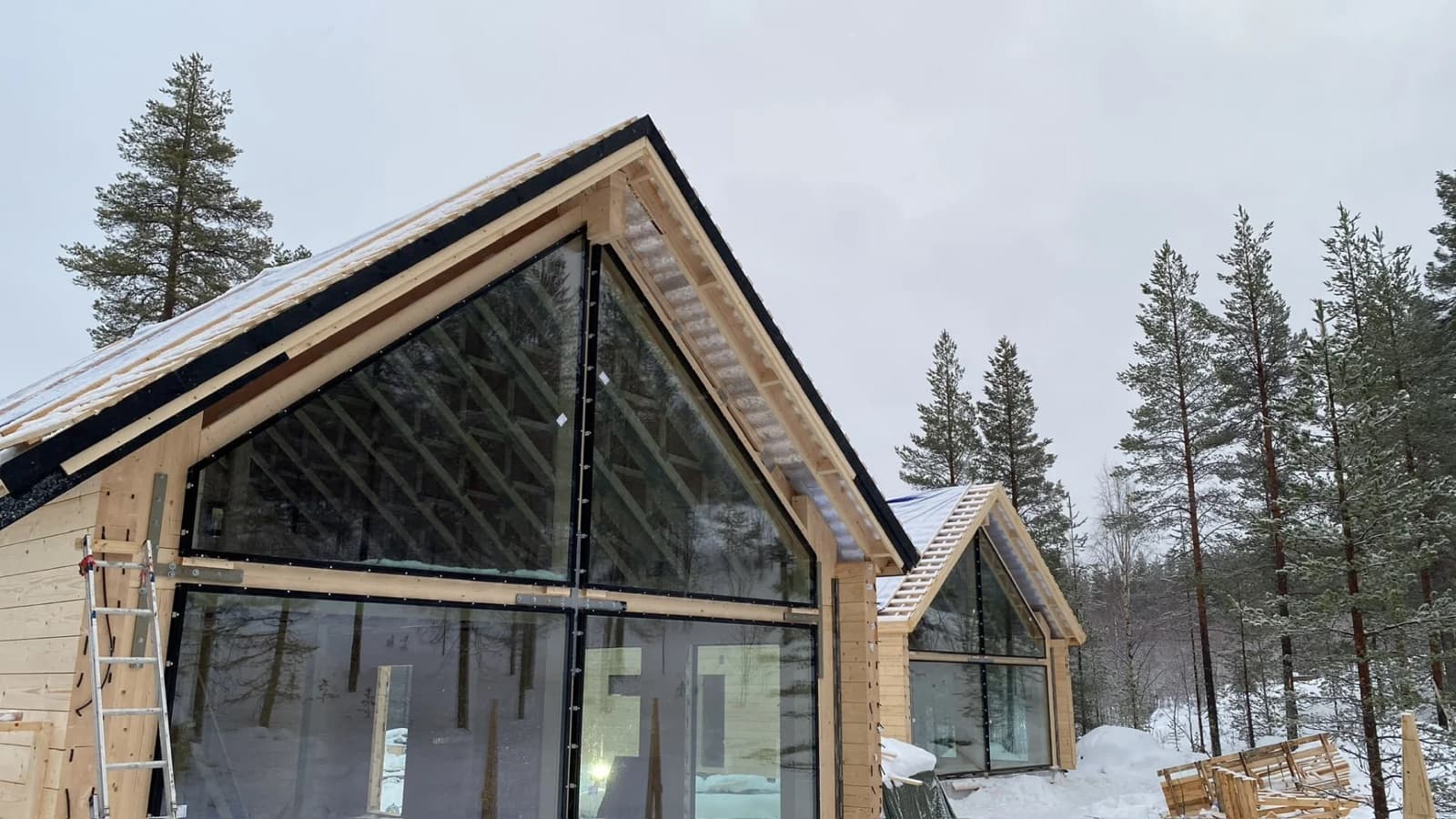Moderni puutalo rakenteilla lumisessa metsässä