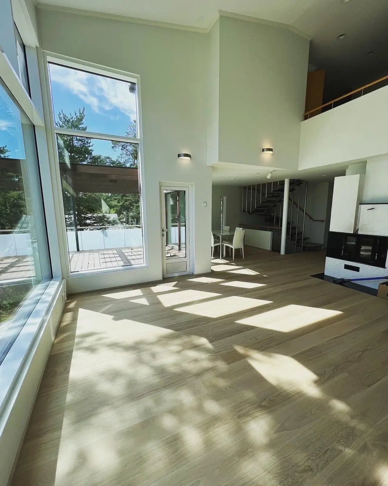 Valoisa olohuone, suuret ikkunat ja puulattia